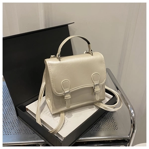 Detail of off-white pearl luster backpack featuring dual buckles and textured PU leather
