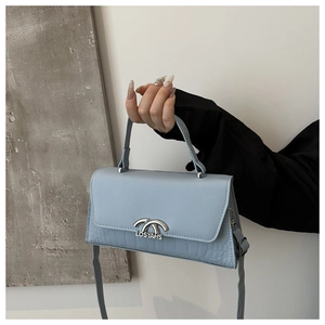 Detail of light blue crossbody bag featuring crocodile embossed leather and silver logo buckle
