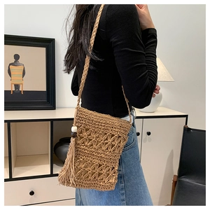Detail of bohemian woven straw crossbody bag featuring floral patterns and wood bead tassels