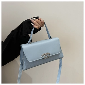 Detail of light blue crossbody bag with crocodile embossed texture and metal clasp