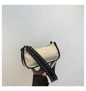Detail of straw woven handbag with black leather trim and silver studded wide strap