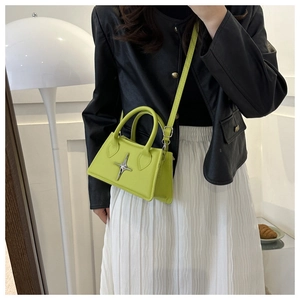 Détail du sac à main vert fluo avec étoile argentée porté par un mannequin de mode