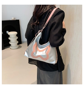 Detail einer silbernen Metallic-Schultertasche mit rosa Wellenmuster an einem Model