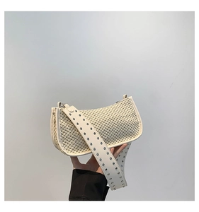 Detail of off-white straw woven bag featuring a wide PU strap with metal grommet studs