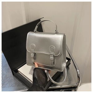 Close-up of silver metallic backpack with double buckle flap and accordion fold structure