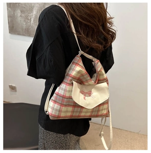 Detail of red and white plaid tote bag featuring a pink bow flap pocket on the front