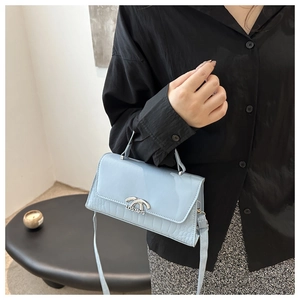 Detail of light blue croc-effect leather handbag with silver semi-circular metal buckle