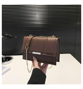 Detail of brown leather bag with accordion design and gold chain shoulder strap