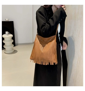 Close-up of brown fringe shoulder bag with metal eyelets on model for size reference