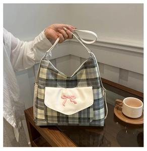 Close-up of plaid tote bag featuring a white front pocket with pink bow embroidery detail