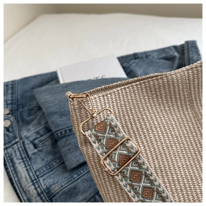 Detail of beige woven tote bag with bohemian geometric embroidery strap and gold hardware
