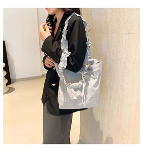 Detail of grey ruffled shoulder strap and delicate rhinestone accents on a stylish tote