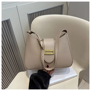 Detail view of beige PU leather hobo bag with adjustable gold buckle strap on chair