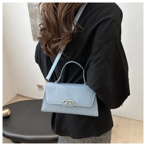 Detail of light blue crossbody bag showing faux crocodile texture and silver LOSYAHS buckle