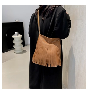 Detail of brown bohemian fringe tote bag with metal eyelets on a black blazer
