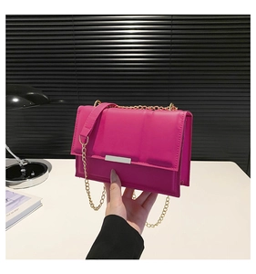 Detail view of fuchsia quilted crossbody bag with gold chain strap and polished finish