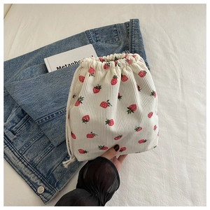 Détail d'un sac en velours côtelé beige à cordon avec motif fraise rouge mignon