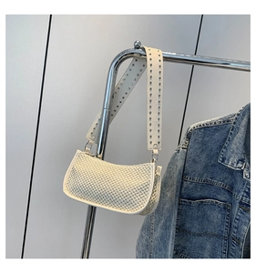 Detail of straw woven bag texture with rivet-embellished leather strap in cream white
