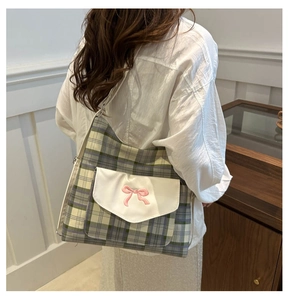 Detail of checkered tote bag with embroidered pink bow and a white front flap pocket
