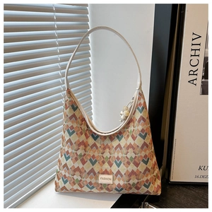 Detail of colorful geometric woven tote bag with FASHION label and bead charm on a counter