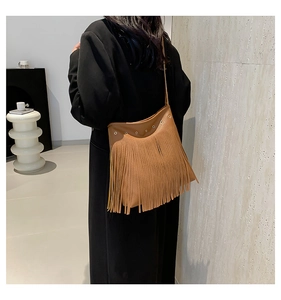 Detailed view of a brown leather tote with long fringes and metal eyelets on a model