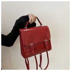 Detail of red patent leather backpack featuring silver buckles and glossy finish