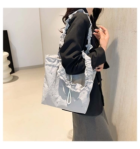 Detail of grey tote bag with pleated shoulder strap, pearl accents and drawstring closure