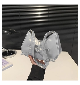 Détail du sac demi-lune argenté métallisé avec nœud décoratif et finition miroir lisse
