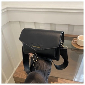 Detail of black leather square bag featuring a pointed flap and fashion logo plaque