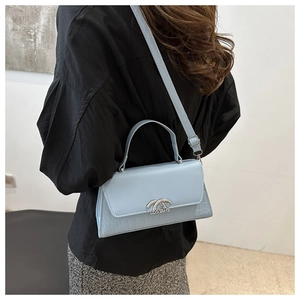 Detail of light blue faux leather crossbody bag with crocodile pattern and silver ring