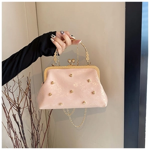 Dettaglio borsa rosa con borchie a cuore dorate e manico decorato stile lusso