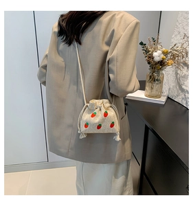 Detailed strawberry embroidery on straw woven bucket bag with drawstring closure