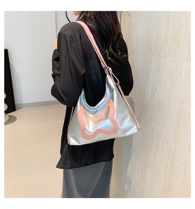 Detail der silbernen Hobo-Tasche mit rosa Lederschleife und Metallkettengurt