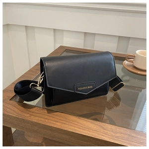 Detail of minimalist black crossbody bag with gold fashion lettering and wide strap