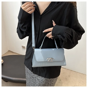 Detail of blue faux-croc crossbody bag with silver hardware and adjustable shoulder strap