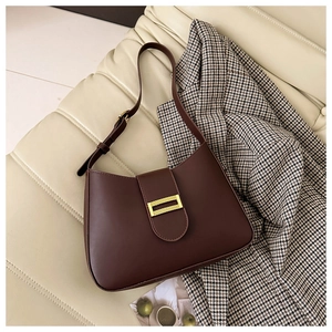 Detail of dark chocolate matte leather bag with vintage golden metal buckle on ivory sofa