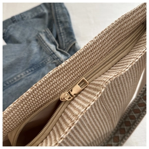 Detailed close-up of woven bucket bag with metal zipper and ethnic patterned strap