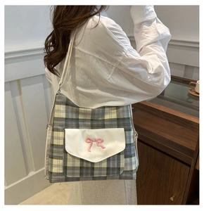 Close-up of classic blue-green plaid canvas bag with pink bow embroidery detail