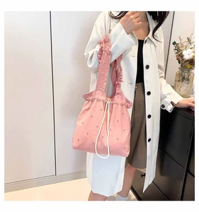 Detailed view of pink pleated tote bag with pearl accents and drawstring closure