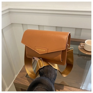 Brown leather crossbody bag detail with triangular flap and golden metal buckle