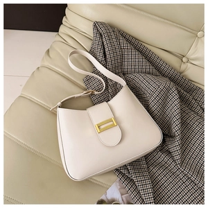 Macro detail of creamy white hobo bag with gold metal buckle on houndstooth background