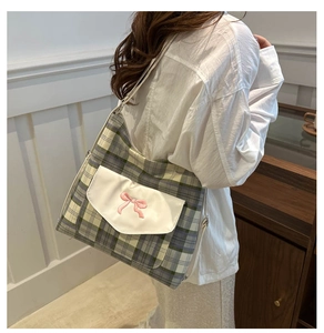 Close-up of green and white plaid tote bag featuring a pink bow and white pocket detail
