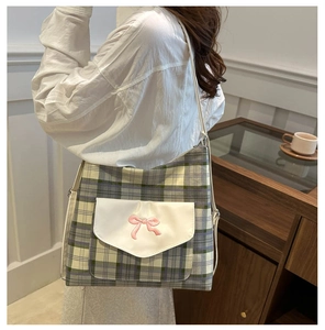 Detail of grey-green plaid tote bag with white flap pocket and pink bow embroidery