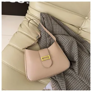 Detail of beige shoulder bag with gold rectangular buckle on soft textured background
