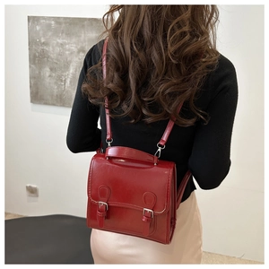 Detail of dark red glossy leather backpack with buckle closure on a model