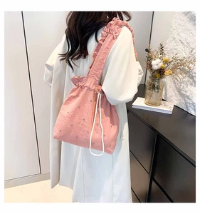 Pink pleated tote bag with drawstring closure and silver bead details on model