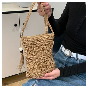 Detail of bohemian straw bag with diamond hollow pattern and beaded tassel charm