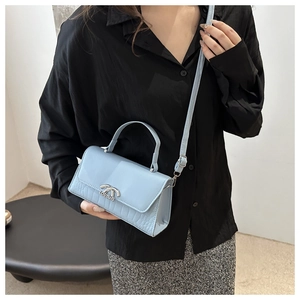 Close-up of glacier blue crossbody bag featuring crocodile texture and metal logo clasp