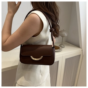 Détail d'un sac bandoulière marron foncé avec boucle dorée en croissant et bandoulière nouée
