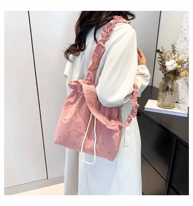 Pink drawstring tote bag featuring rhinestone embellishments and ruffled shoulder strap